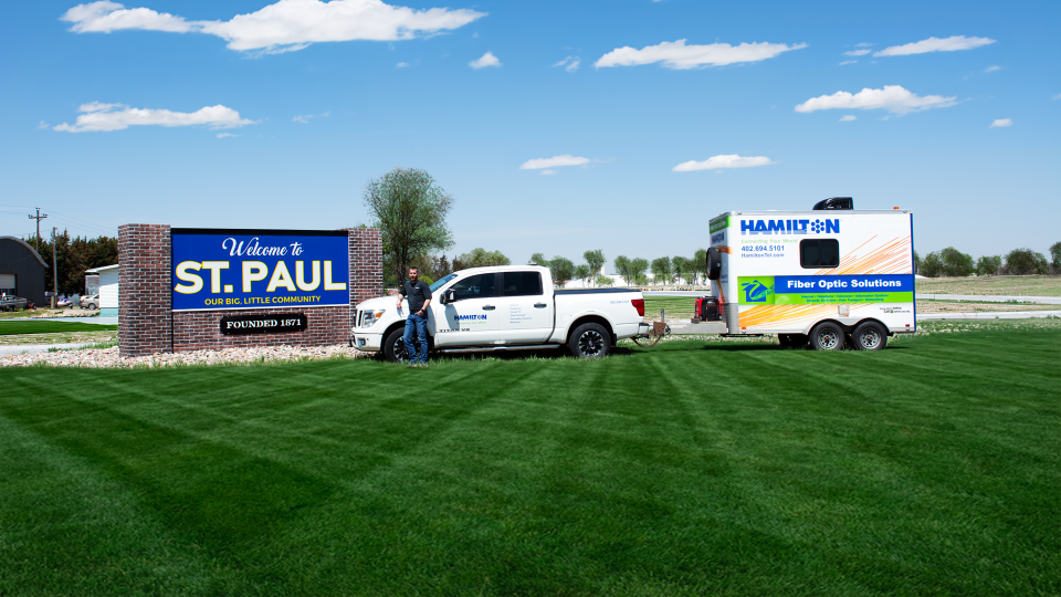 Hamilton fiber tech standing in front of St. Paul town sign